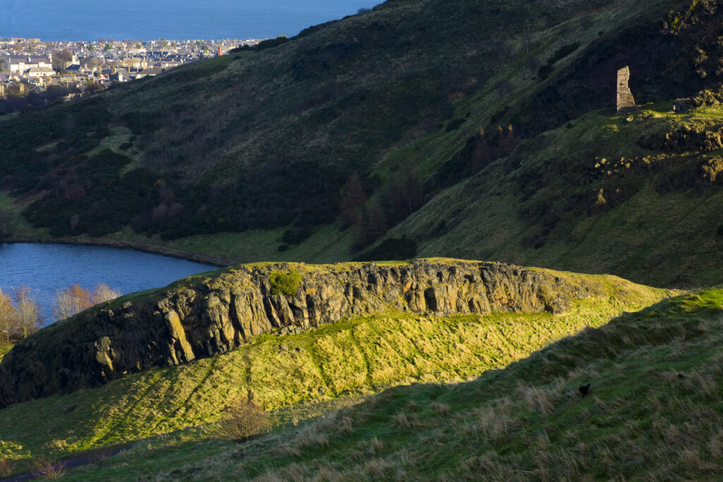 Scotland, Edinburgh, Holyrood Park. St Anthony's Chapel high above St Margaret's Loch, viewed from the Salisbury Crags.