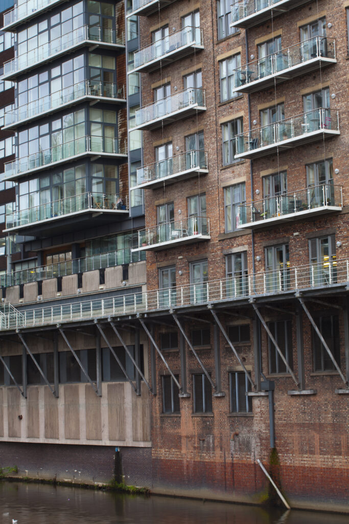 England, Greater Manchester, Manchester. Detail shot of modern apartments formed by redevolping Victorian warehouses located on the banks of the River Irwell near the Trinity Bridge.