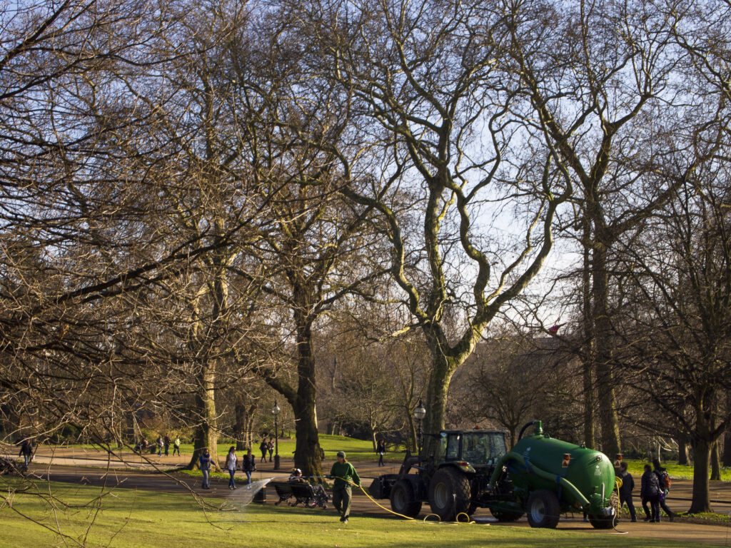 England, London, Hyde Park. Council worker watering grass in Hyde Park, a popular green space near the city center of London.