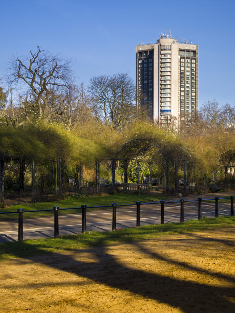 England, London, Hyde Park. Trees on the edge of Hyde Park, with modern buildings and architecture in the background.