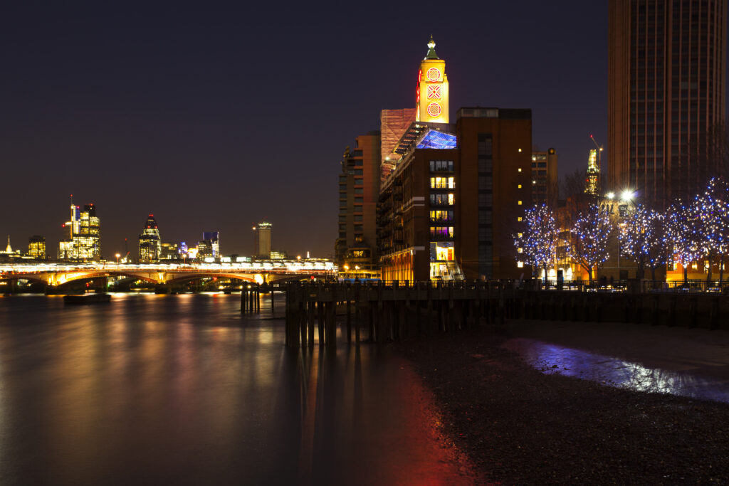 England, London, OXO Tower. The OXO Tower viewed from upstream of the River Thames, with Sea Containers House and the City Of London and Gherkin building beyond.