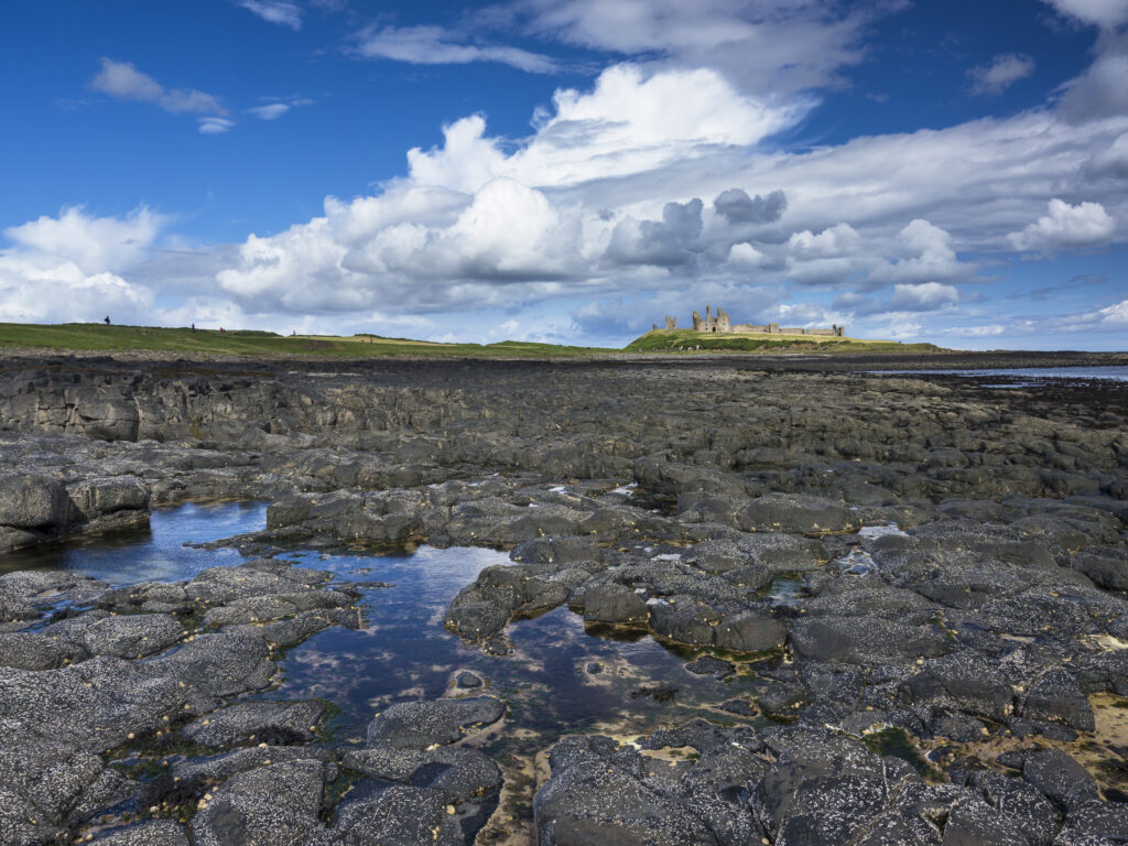 England, Northumberland, Dunstanburgh Castle. Dunstanburgh Castle and surrounding coastline at low tide.