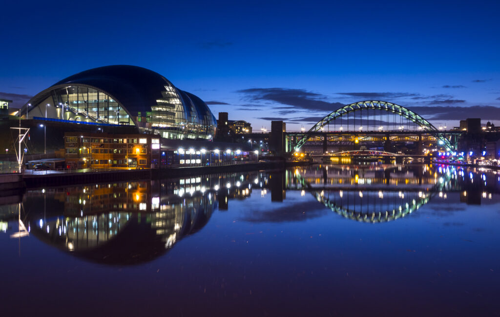 England, Tyne and Wear, Newcastle Upon Tyne. The Sage Building and the Tyne Bridge crossing the River Tyne and joining the Newcastle / Gatehead Quayside.