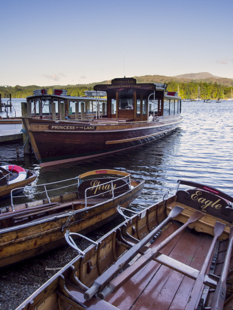 England, Cumbria, Lake District National Park. Tourist pleasure boat and rowing boats moored in Ambleside on Lake Windermere.