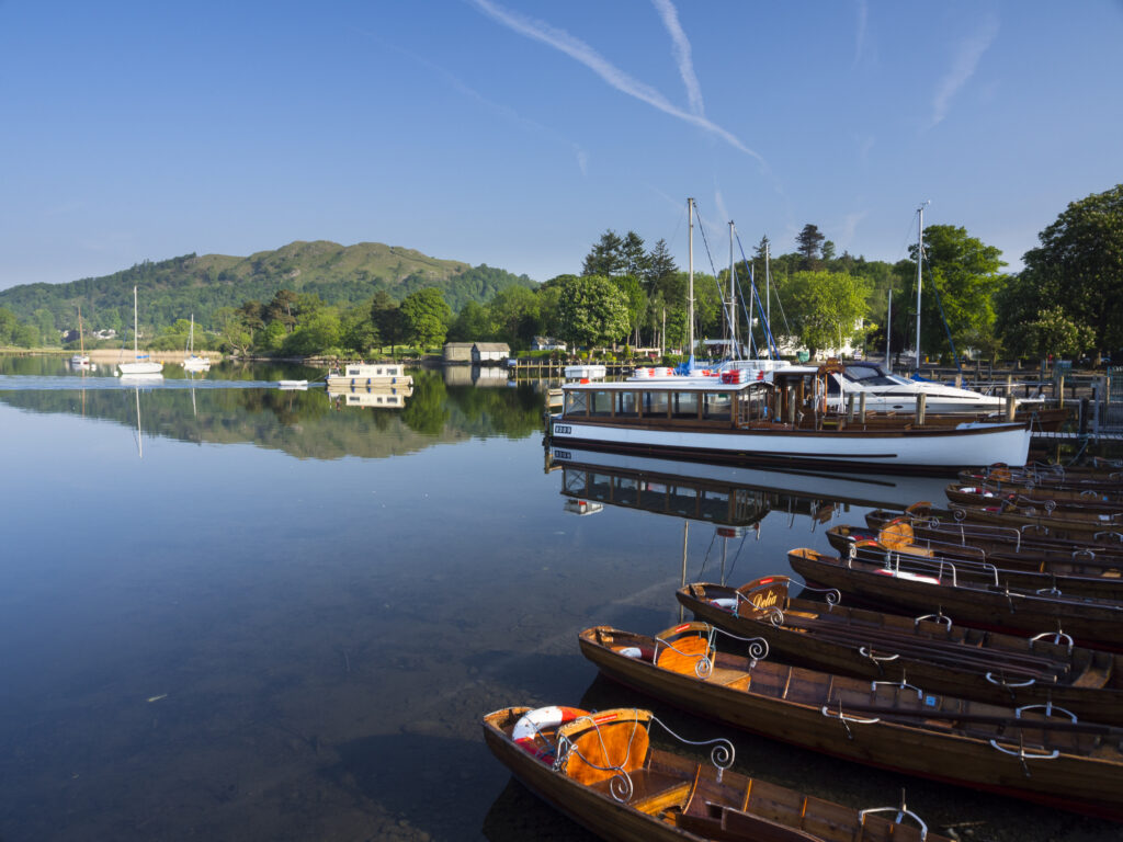 England, Cumbria, Lake District National Park. Tourist pleasure boat and rowing boats moored in Ambleside on Lake Windermere.