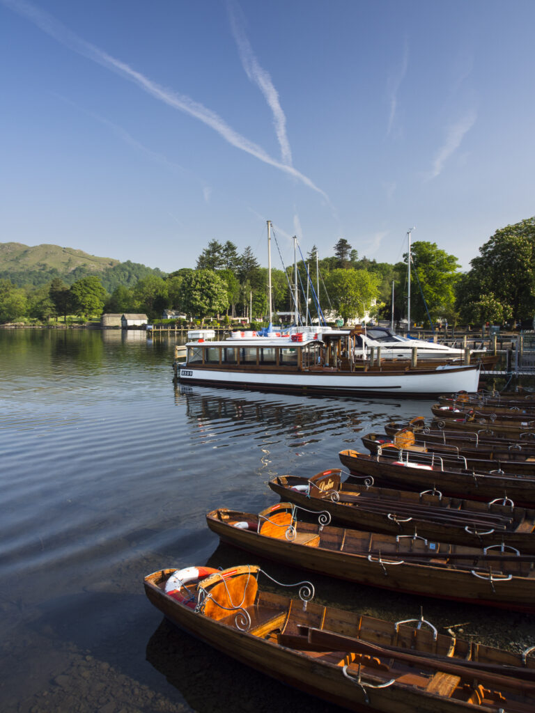 England, Cumbria, Lake District National Park. Tourist pleasure boat and rowing boats moored in Ambleside on Lake Windermere.