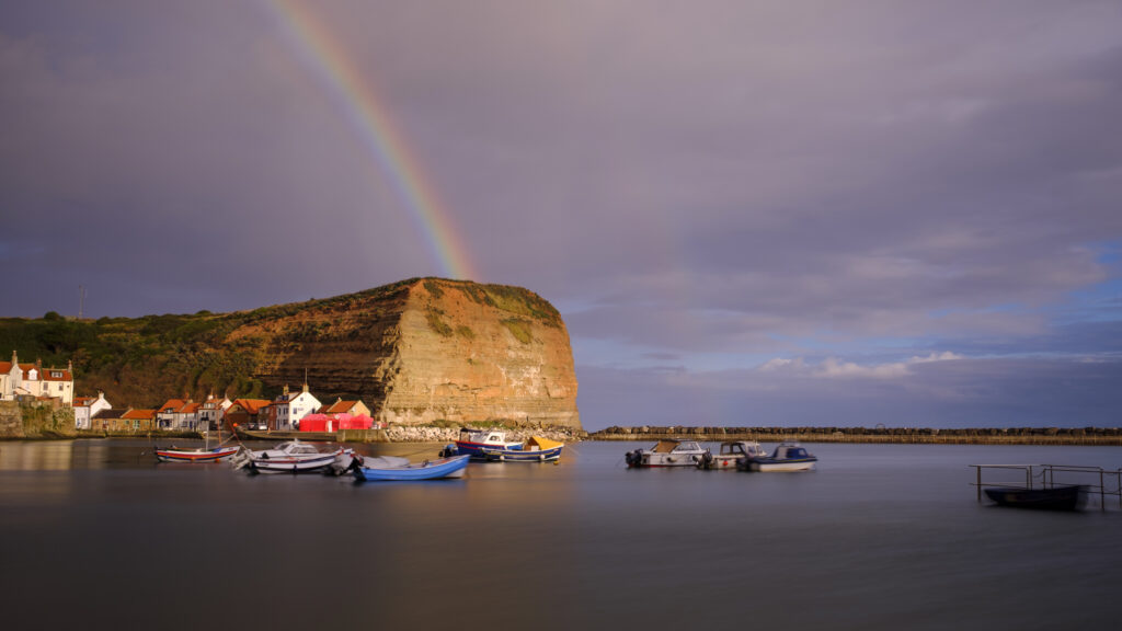 England, North Yorkshire, North York Moors National Park. Rainbow and early morning light at Staithes, a coastal village in the North York Moors National Park.