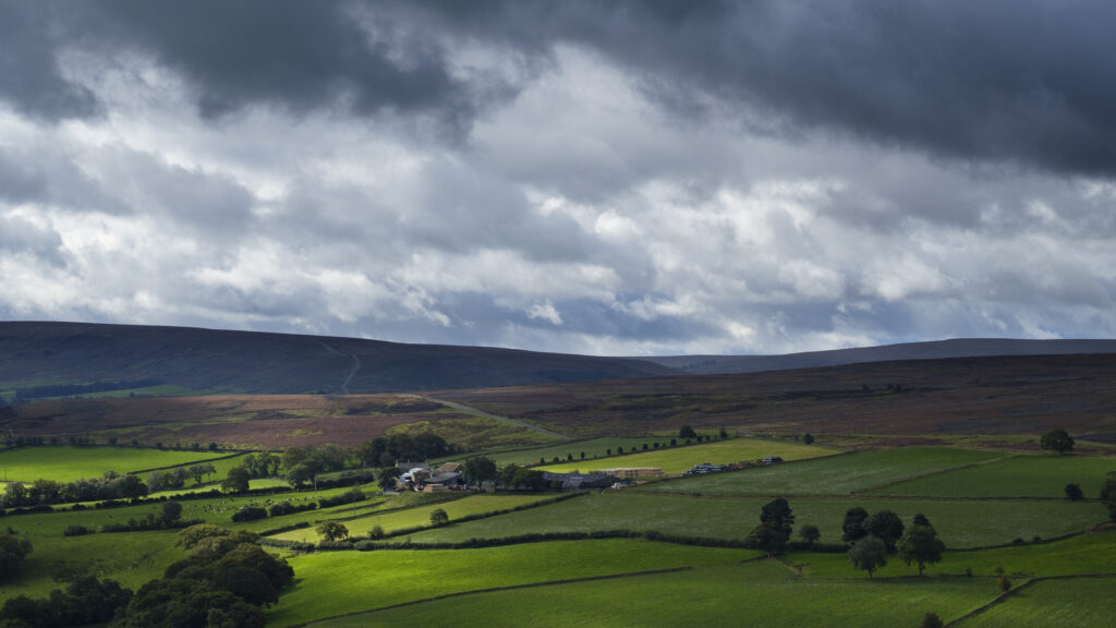England, North Yorkshire, North York Moors National Park. Breaking storm light over the fields and valleys of the North York Moors National Park.