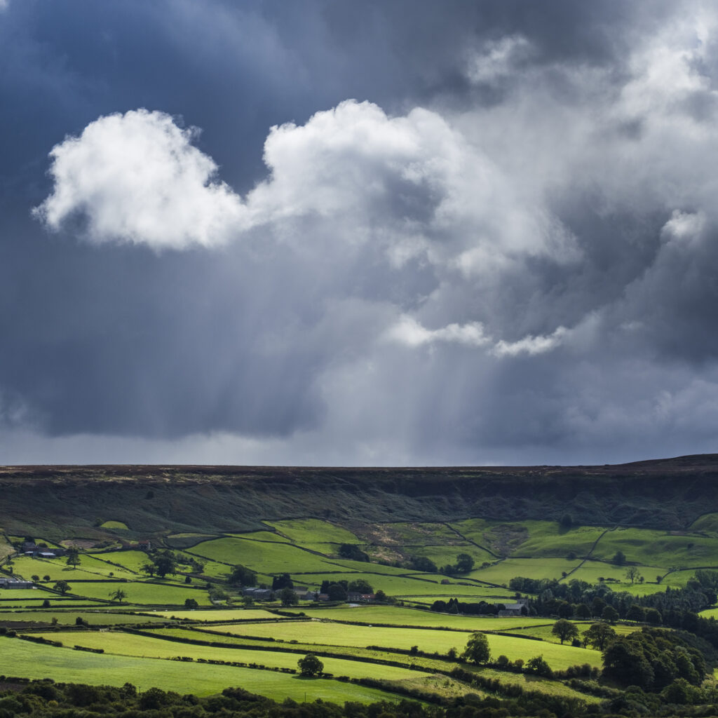 England, North Yorkshire, North York Moors National Park. Breaking storm light over the fields and valleys of the North York Moors National Park.