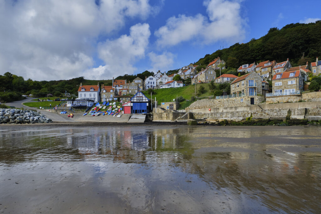 England, North Yorkshire, Runswick Bay. Small coastal village reflected in the wet, low tide, sand of Runswick Bay.
