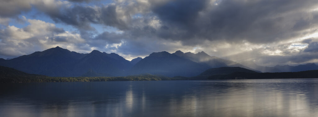New Zealand, Southland, Lake Manapouri. Storm clouds over the mountain peaks of Fiordland National Park viewed from Fraser Beach at Manapouri.