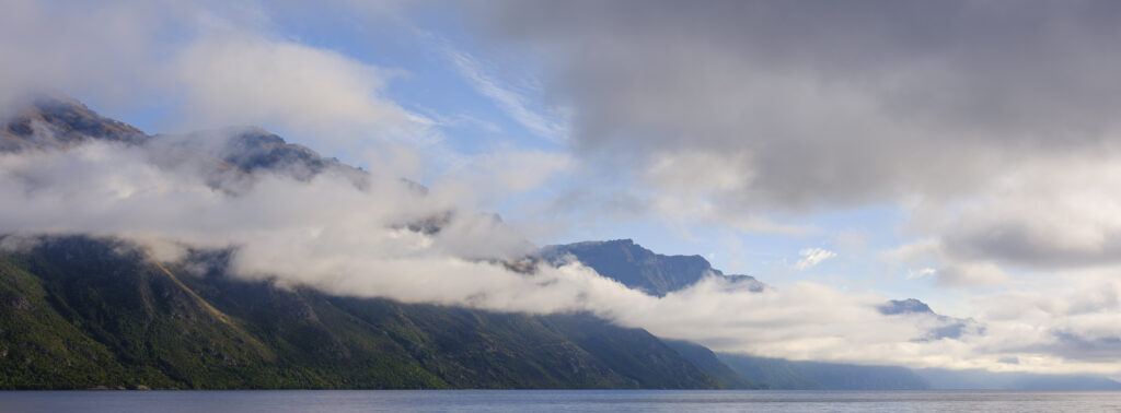 New Zealand, Otago, Lake Wakatipu. Morning mist clings to the mountains above Lake Wakatipu near the tourist hotspot of Queenstown.