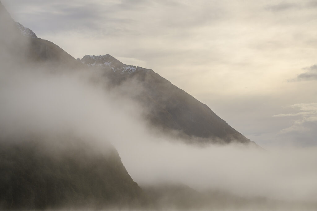 New Zealand, South Island, Fiordland National Park. Clearing mist above native woodland and the mountains surrounding Lake Gunn in Fiordland National Park.