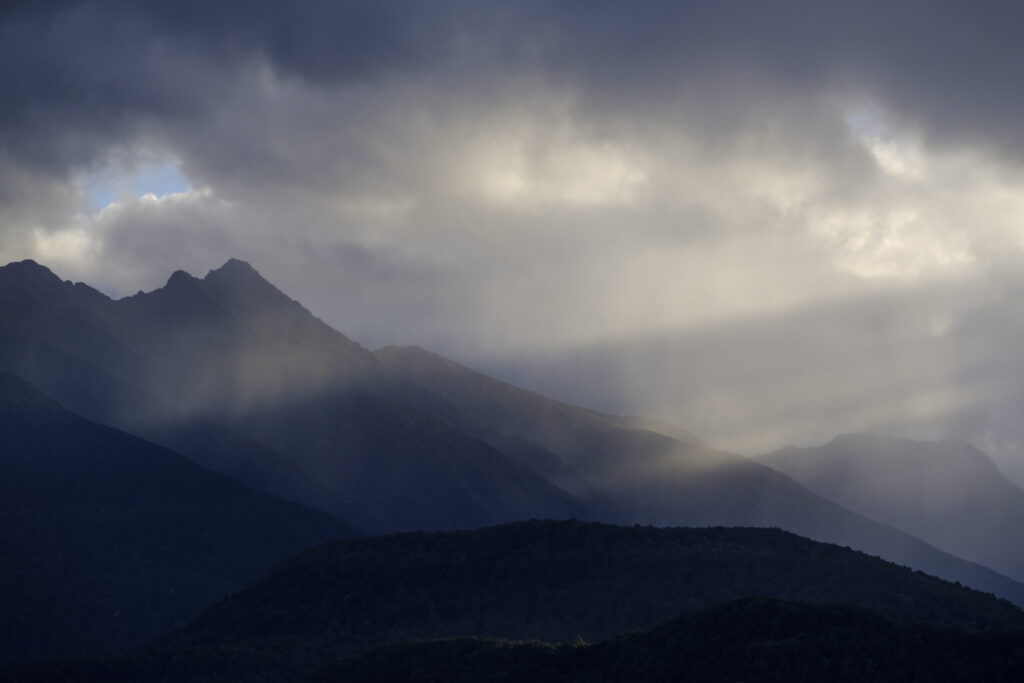 New Zealand, Southland, Lake Manapouri. Storm clouds over the mountain peaks of Fiordland National Park viewed from Fraser Beach at Manapouri.