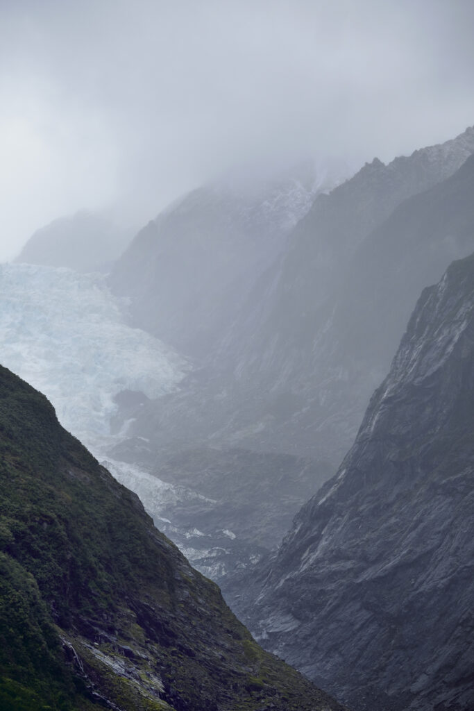 New Zealand, Westland, Westland National Park. Rain clouds hug the peaks of the valley carved by the retreating Franz Josef Glacier.