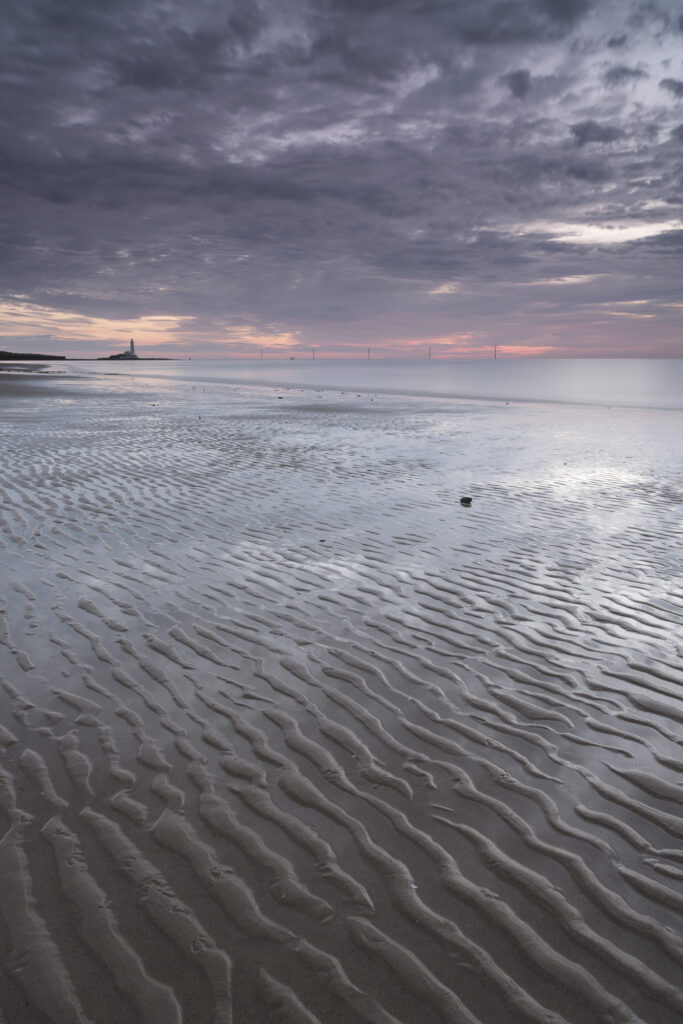 England, Tyne and Wear, Whitley Bay. St Mary's Lighthouse viewed from Whitley Sands shortly after dawn.
