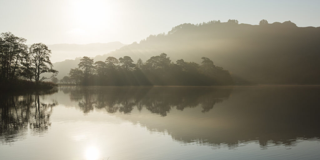England, Cumbria, Lake District National Park. Morning mist at woodland near Rydal Water, on a still autumn day.