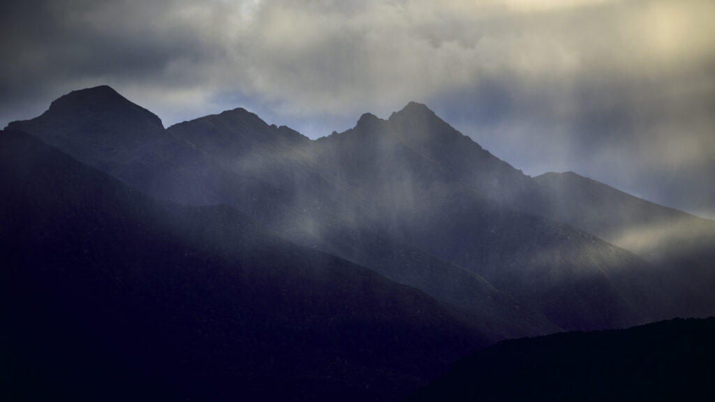 New Zealand, Southland, Lake Manapouri. Storm clouds over the mountain peaks of Fiordland National Park viewed from Fraser Beach at Manapouri.