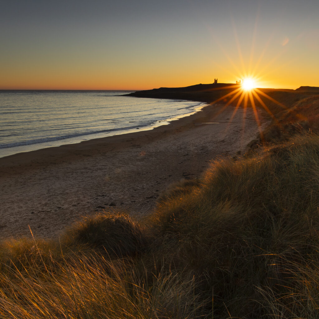 England, Northumberland, Dunstanburgh Castle. Dunstanburgh Castle viewed at dawn from Embleton Bay.