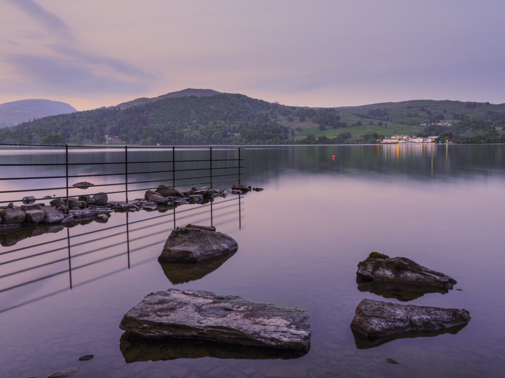 England, Cumbria, Lake District National Park. Shoreline of Low Wray at dusk refelcted in the still waters of Lake Windermere near the town of Ambleside.