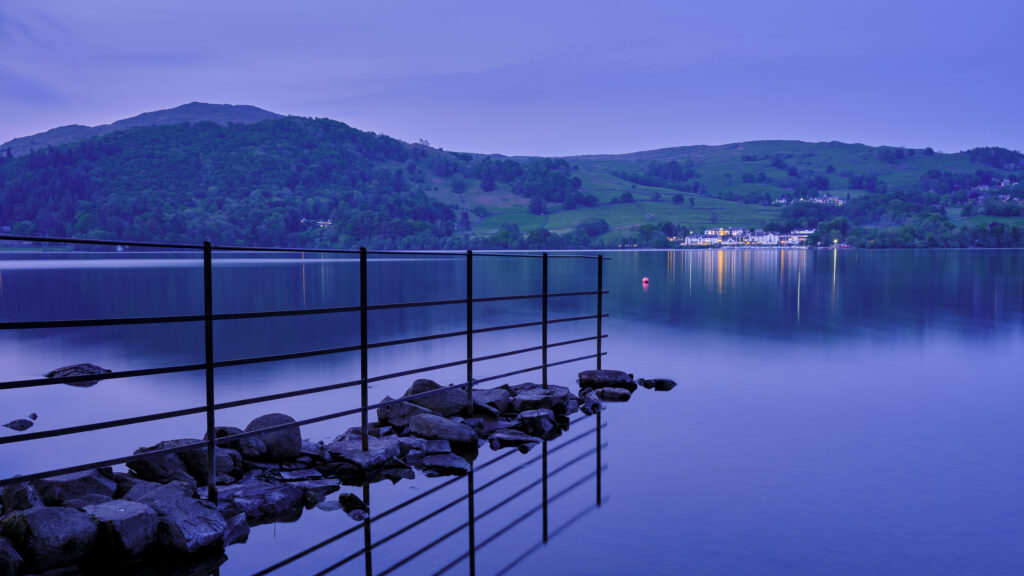 England, Cumbria, Lake District National Park. Shoreline of Low Wray at dusk refelcted in the still waters of Lake Windermere near the town of Ambleside.