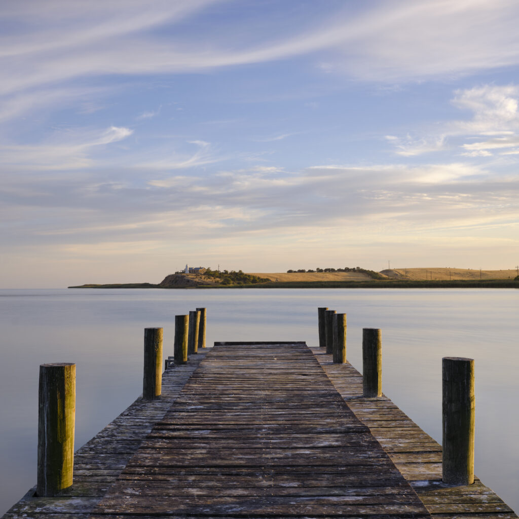 Australia, Southern Australia, Narrung Jetty Reserve. The Narrung Jetty looking across the Lake Alexandrina Narrows towards the Point Malcolm Lighthouse.