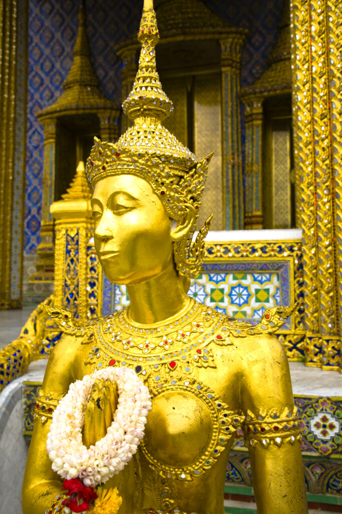 Thailand, Bangkok, The Grand Palace. Statue in the ornate setting of the golden grand palace.