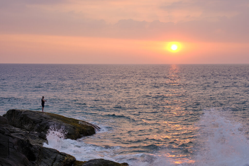 Sri Lanka, Galle District, Ahungalla. A fisherman enjoys a golden sunset.
