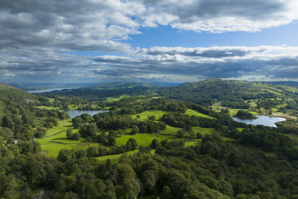 England, Cumbria, Lake District National Park. Aerial view of Elterwater, Loughrigg Tarn and Lake Windermere looking south towards the southern lake district.