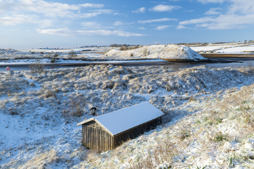 England, Northumberland, Alnmouth. Snow covered sand dunes near the mouth of the Aln Estuary at Alnmouth. The hill in the distance is known as Church Hill.
