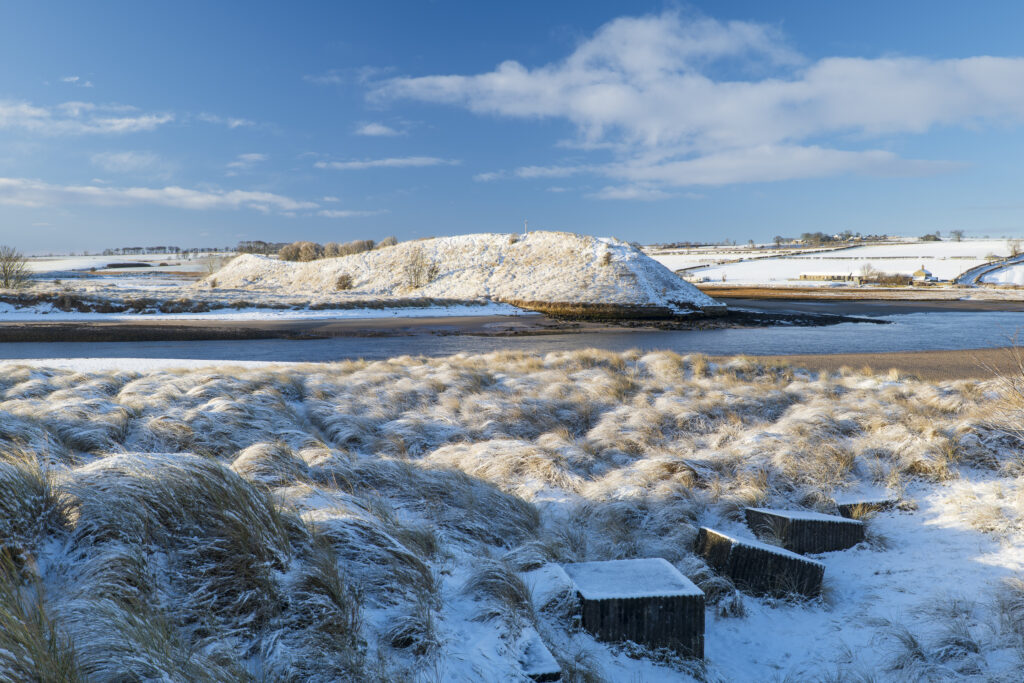 England, Northumberland, Alnmouth. Snow covered sand dunes near the mouth of the Aln Estuary at Alnmouth. The hill in the distance is known as Church Hill.