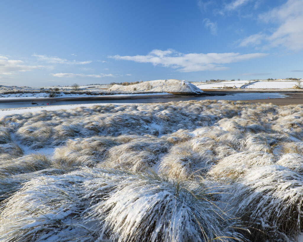 England, Northumberland, Alnmouth. Snow covered sand dunes near the mouth of the Aln Estuary at Alnmouth. The hill in the distance is known as Church Hill.