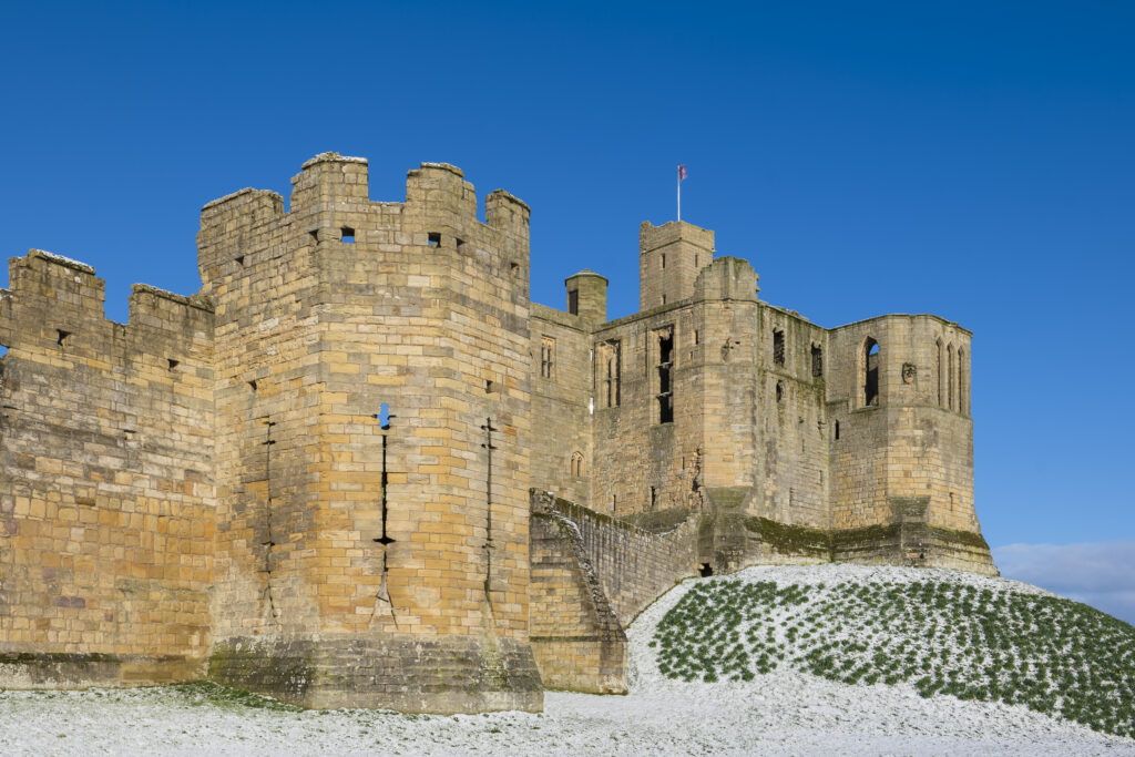England, Northumberland, Warkworth Castle. Warkworth Castle (English Heritage), a magnificent 12th century stone motte and bailey fortress, and surrounding snow covered landscape on a winter morning.