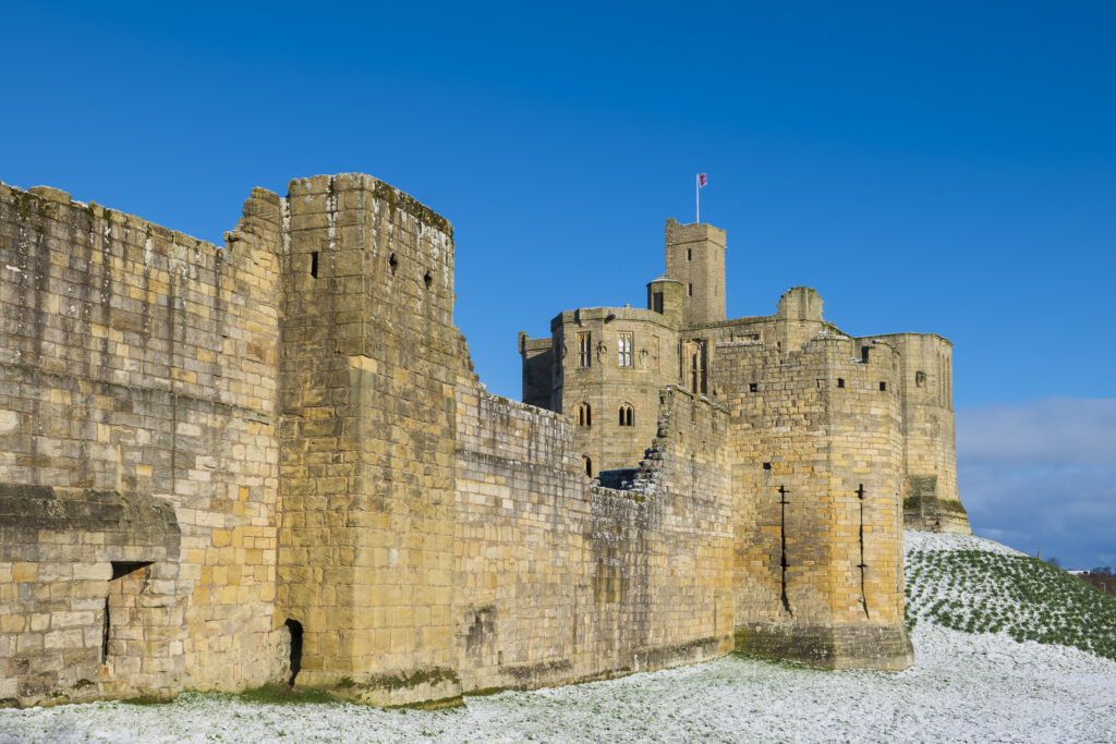 England, Northumberland, Warkworth Castle. Warkworth Castle (English Heritage), a magnificent 12th century stone motte and bailey fortress, and surrounding snow covered landscape on a winter morning.