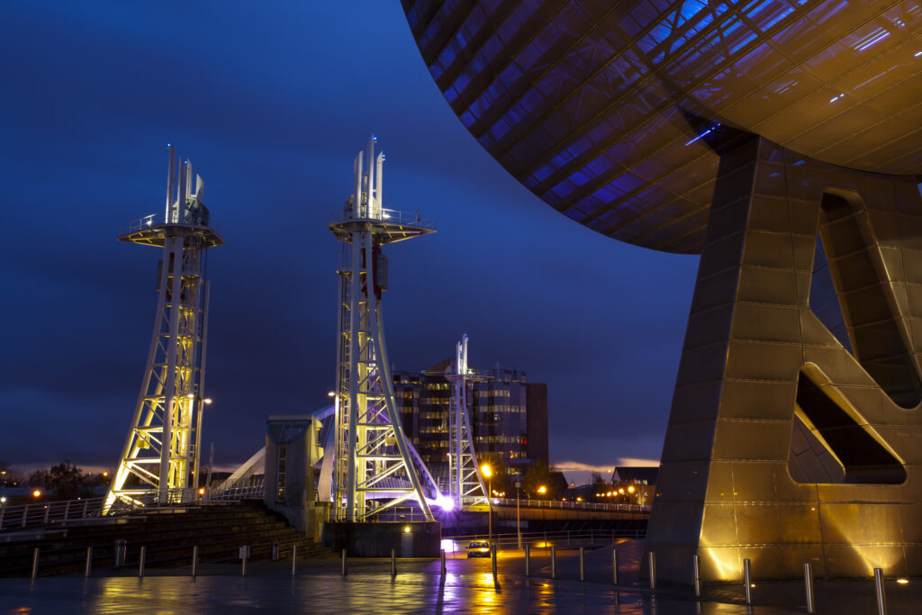 England, Greater Manchester, Salford Quays. The Lowry Centre at dusk looking towards the Lowry Bridge, located on the Salford Quays in the city of Salford near Manchester Old Trafford.