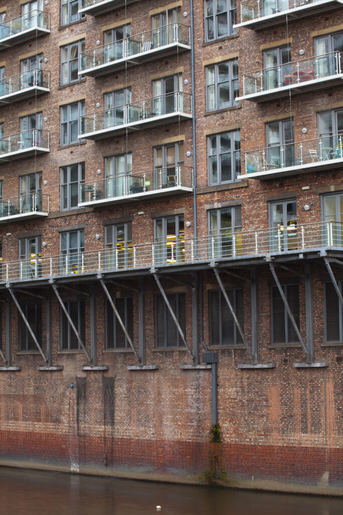 England, Greater Manchester, Manchester. Detail shot of modern apartments formed by redevolping Victorian warehouses located on the banks of the River Irwell near the Trinity Bridge.