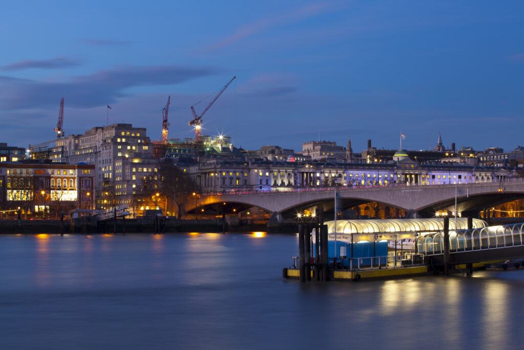 England, Greater London, London South Bank / River Thames. Festival Pier (river boat station), Waterloo Bridge and Somerset House in the distance.