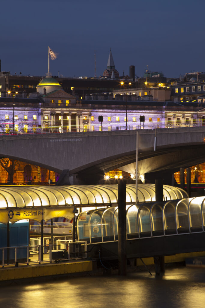 England, Greater London, London South Bank / River Thames. Festival Pier (river boat station), Waterloo Bridge and Somerset House in the distance.