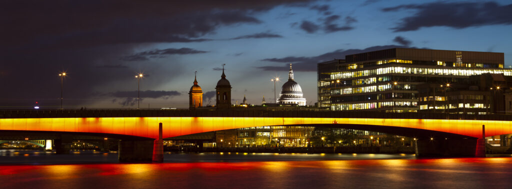 England, Greater London, London City. London Bridge at night, spanning the Rover Thames with St Pauls Cathedral in the distance.