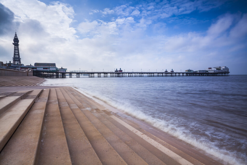 England, Lancashire, Blackpool. Looking towards Blackpool Tower and the North Pier, an historic wooden pier located in the popular northern England seaside resort.