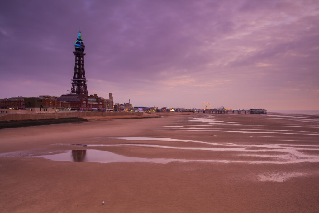 England, Lancashire, Blackpool. Looking towards Blackpool Central Pier and Blackpool Tower at sunset.