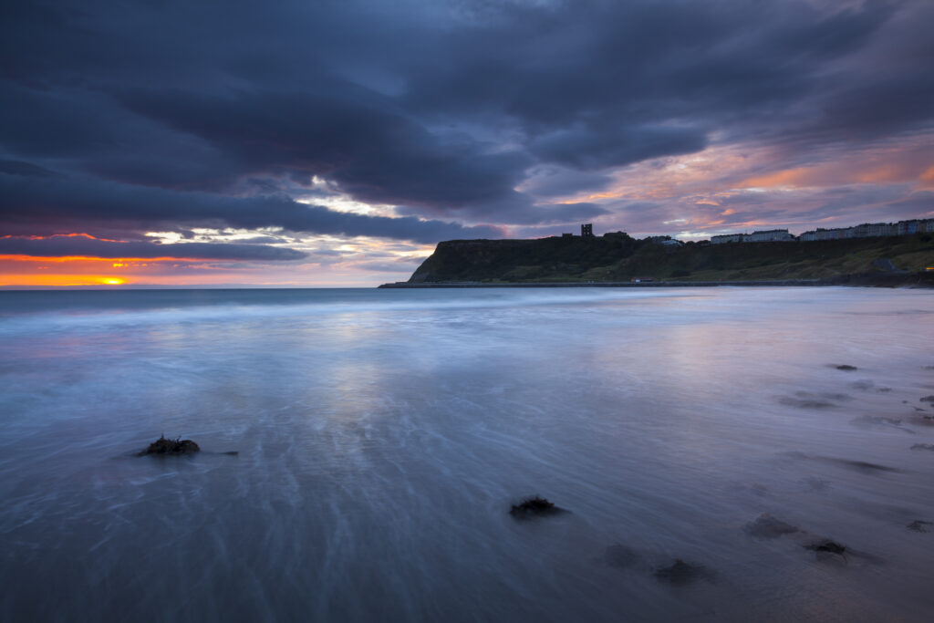 England, North Yorkshire, Scarborough. Dawn at Scarborough South Bay with Scarborough Castle in the distance.