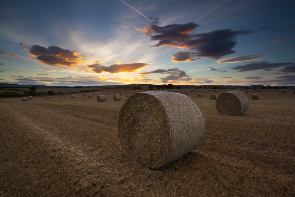 England, North Yorkshire, Scarborough. Sunset clouds above a field and hay bales in North Yorkshire.