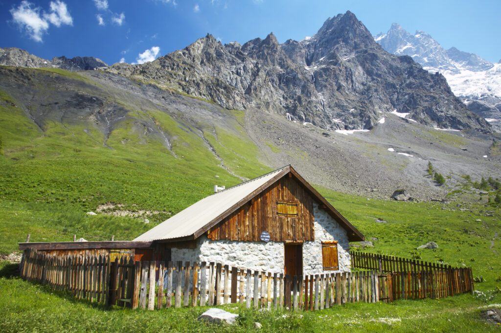 France, Rhône-Alpes, The Ecrins National Park. Wood cabin Chal Vachere loacted on a meadow near the dominating peak of the La Meije