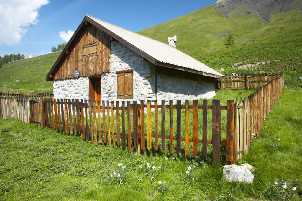 France, Rhône-Alpes, The Ecrins National Park. Wood cabin Chal Vachere loacted on a meadow near the dominating peak of the La Meije