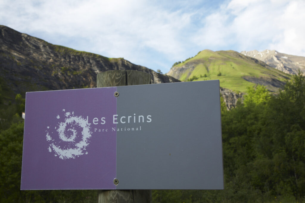 France, Rhône-Alpes, The Ecrins National Park. Ecrins National Park sign within a landscape dominated by mountains near La Grave