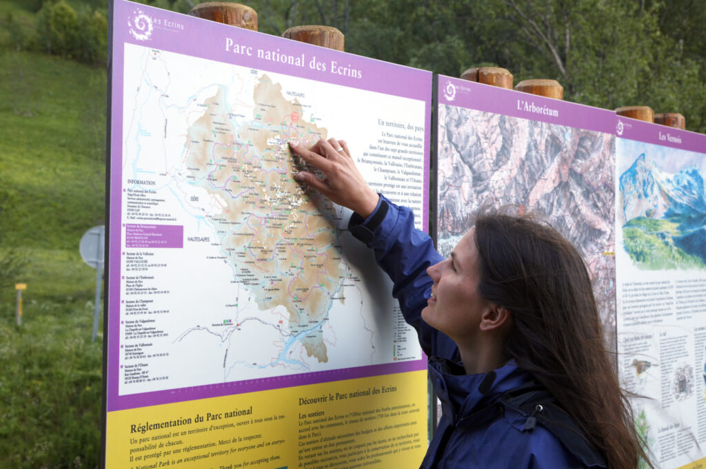 France, Rhône-Alpes, The Ecrins National Park. Female hiker examining a map of the Ecrins National Park near La Grave.