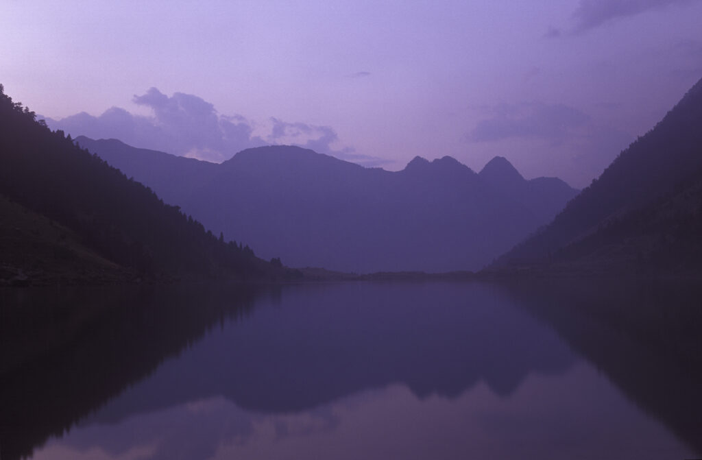 FRANCE, Midi Pyrenees, Pyrenees National Park. Dusk cast a pinkish glow to the lake and surrounding landscape of Lac De Gaub