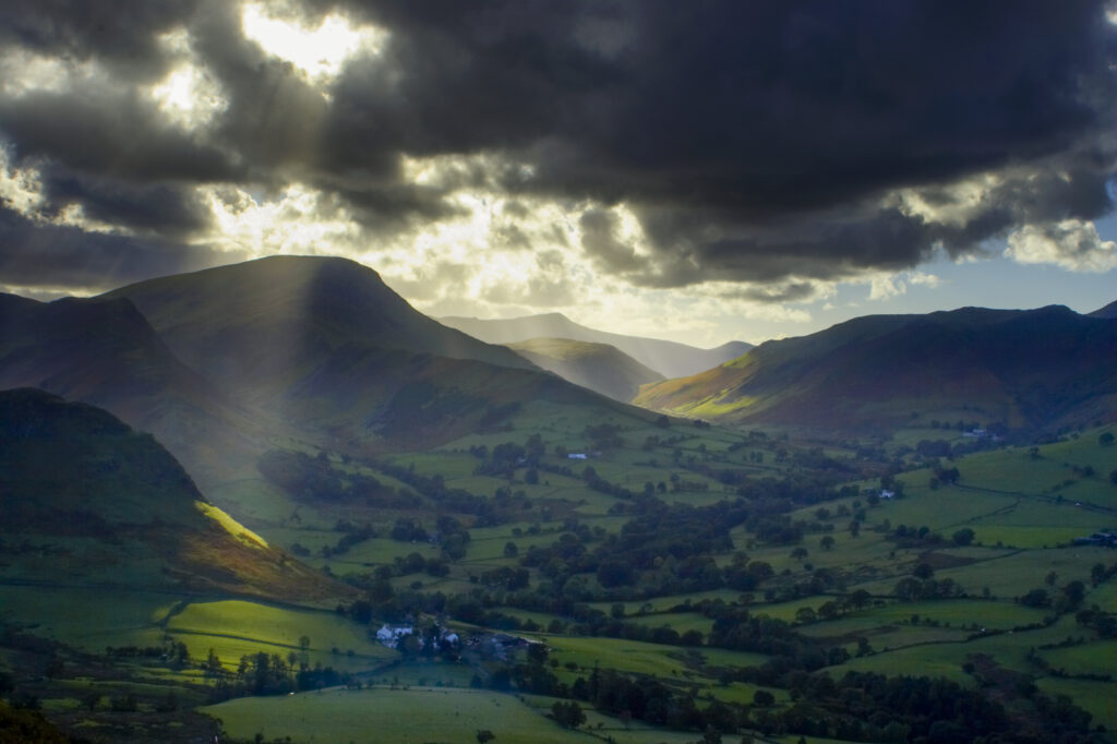 England, Cumbria, Lake District National Park. A shaft of light breaks through storm clouds above the north west lakes.
