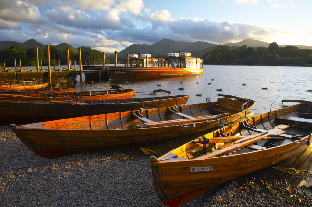 England, Cumbria, Lake District National Park. Wooden rowing boats and Derwent Water cruise ship moored at Jetty on Derwentwater